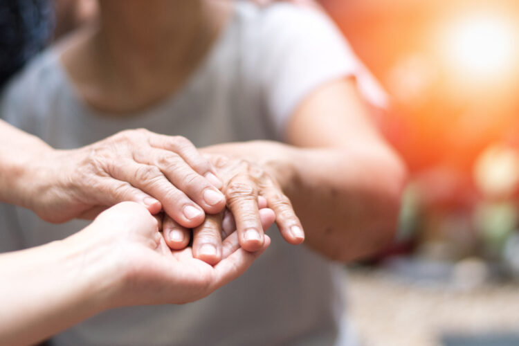 Doctor physician hand on happy elderly senior patient to comfort in hospital examination room or hospice nursing home or wellbeing county.