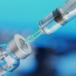 Medical disposable syringe for vaccine injection and glass vial on blue blur background.