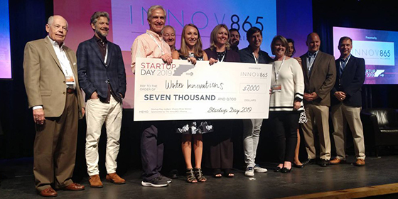 People holding a giant check on a stage at a pitch competition